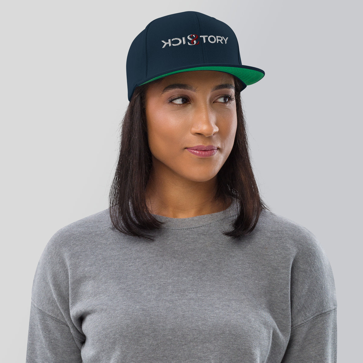 Frau trägt eine dunkelblaue Sick Story Snapback Cap mit besticktem Logo und grüner Schirmunterseite
